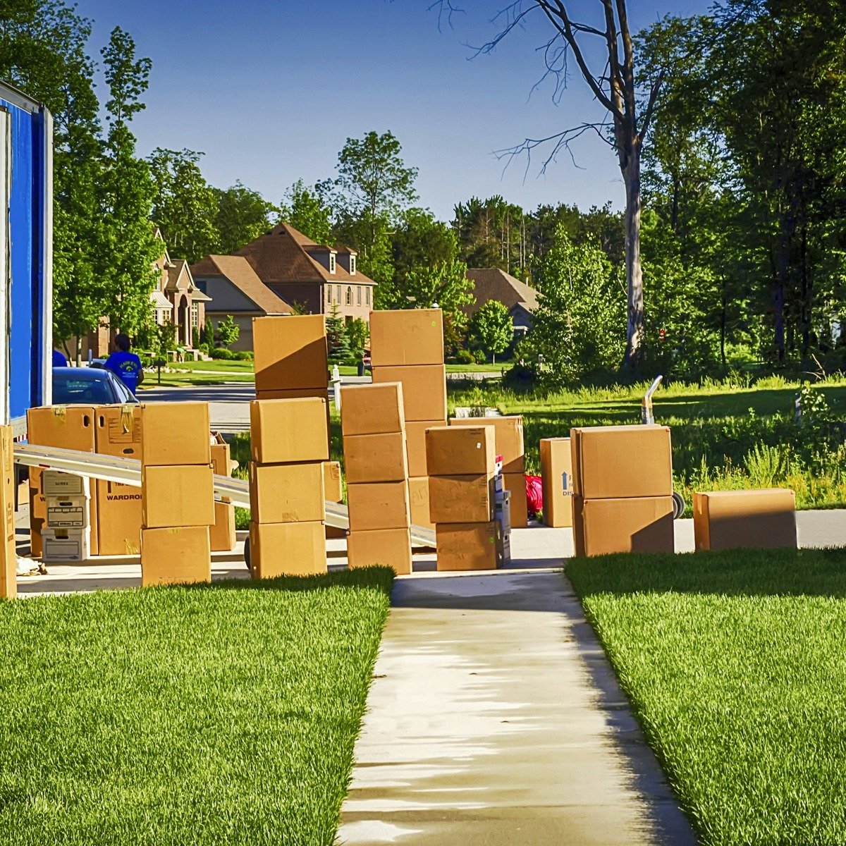 Professional heavy furniture movers unloading packed moving boxes outside a residential home in Encinitas, CA.