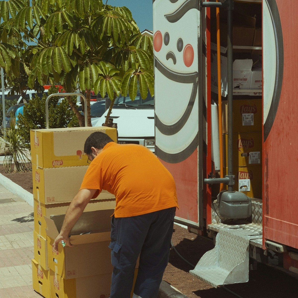 Mover handling stacked boxes beside a moving truck during a heavy furniture move in Carlsbad, CA.