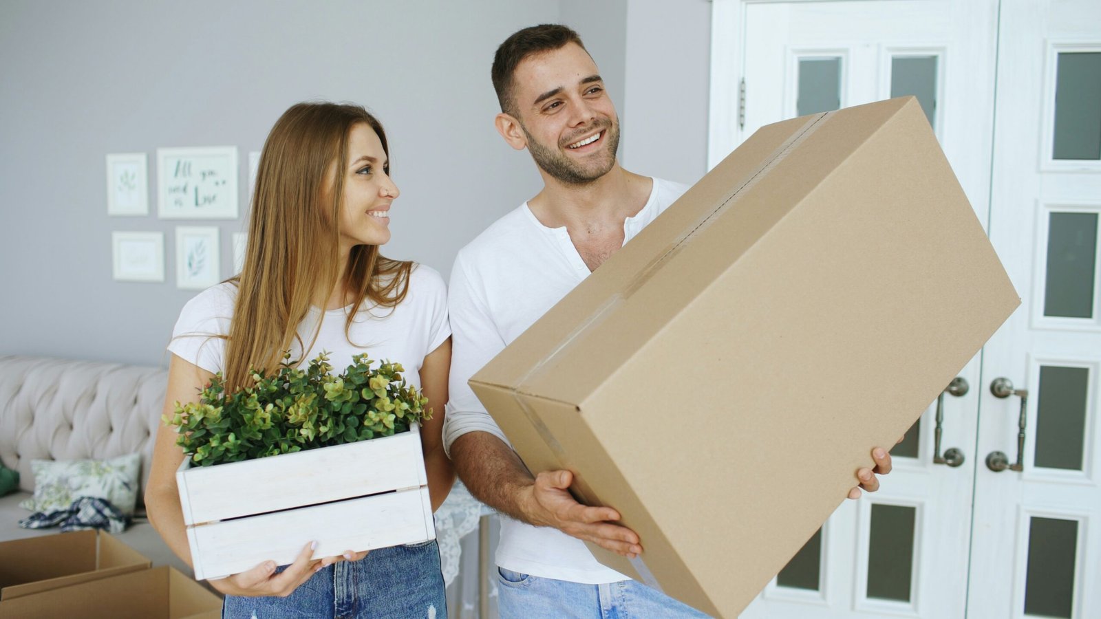 Couple carrying a moving box during residential interstate moving services near me