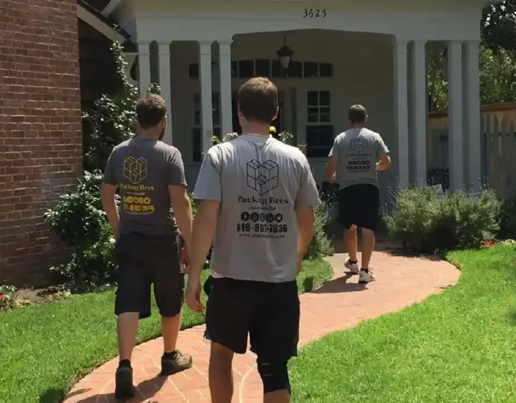Moving team navigating large furniture through a modern Encinitas condo hallway while protecting walls and floors